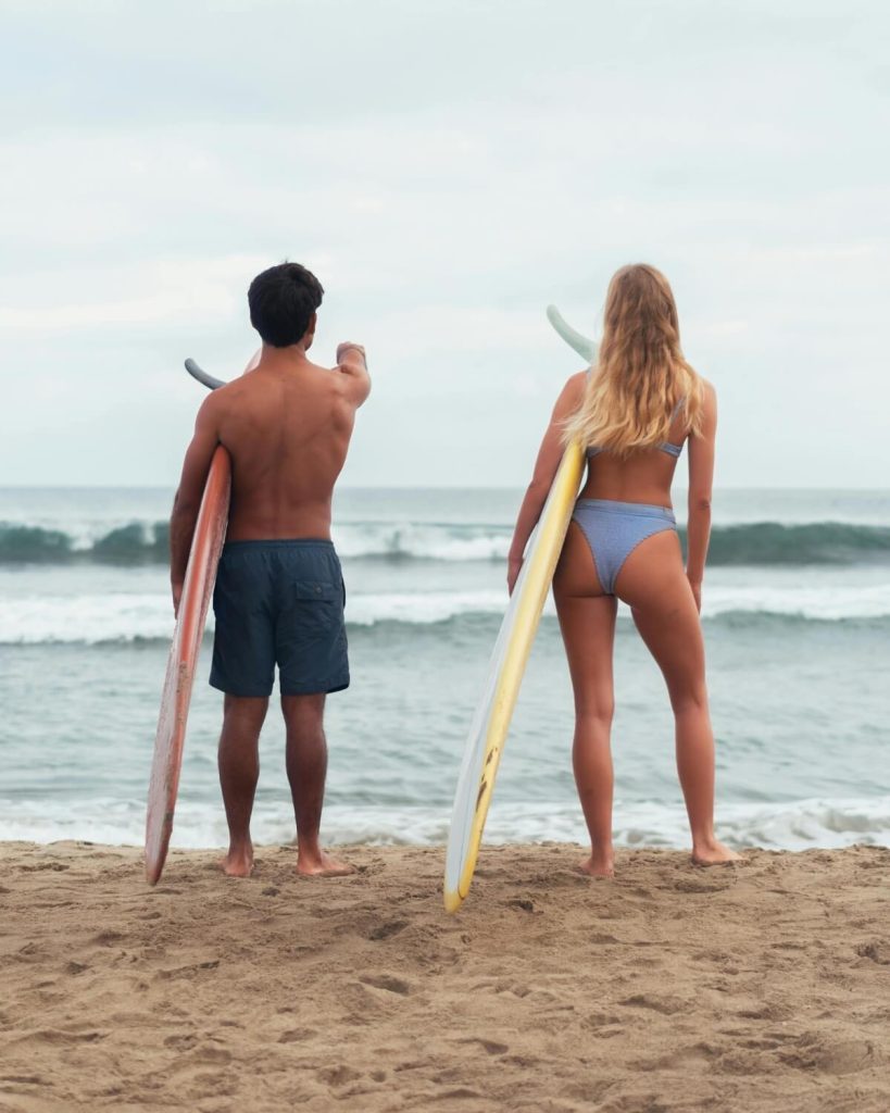 Couple holding surfboards and looking at the ocean in Santa Teresa, Costa Rica
