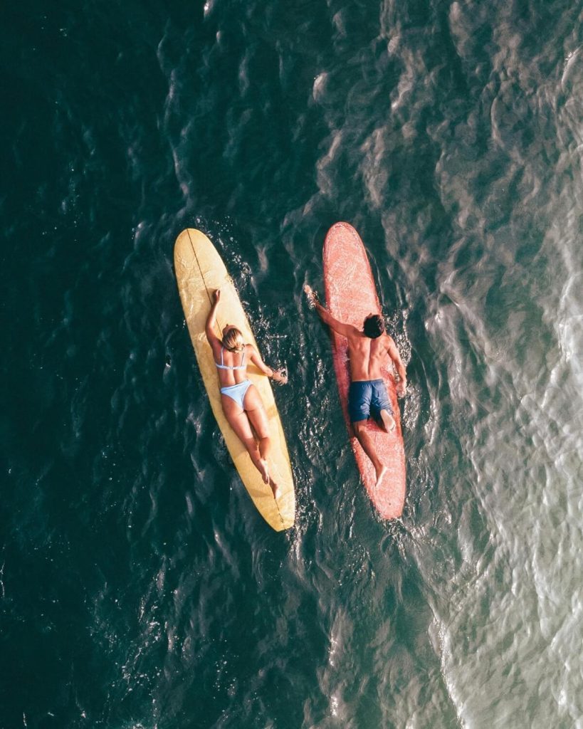 Couple surfing gentle waves in Santa Teresa, Costa Rica, aerial view